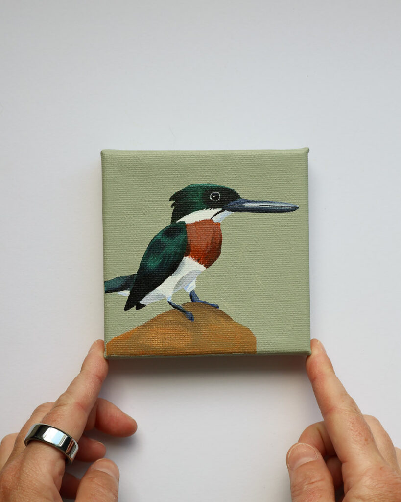 Klein schilderij van een mannelijke groene ijsvogel op een rots tegen een zachte saliegroene achtergrond